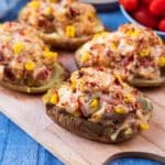 Four stuffed baked potatoes on a wooden serving board