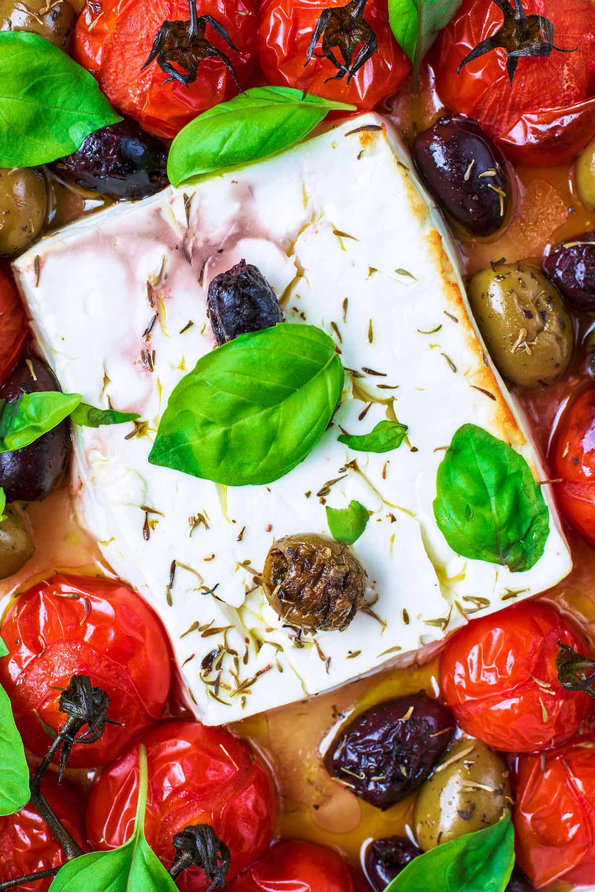 A block of baked feta cheese surrounded by roasted cherry tomatoes.