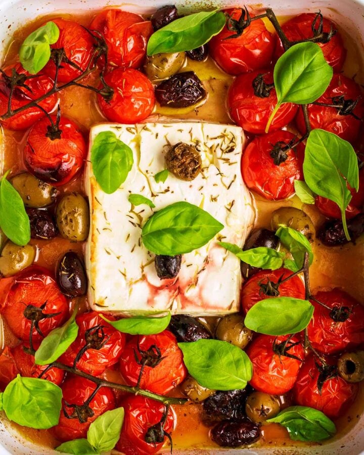Cooked feta, olives and tomatoes in a baking tray.