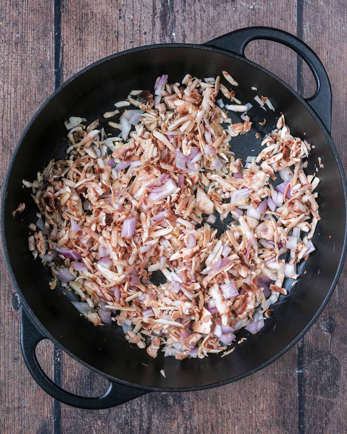 Shallots, mushrooms and garlic cooking in a pan.