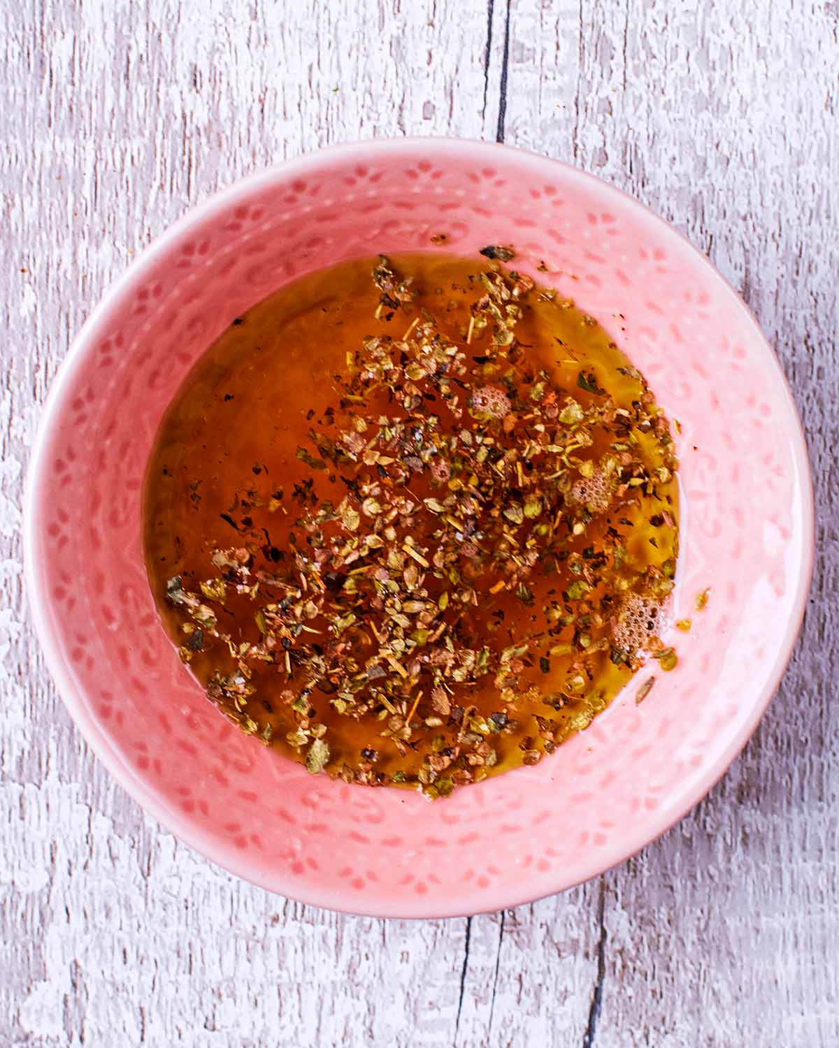 A small dish containing an oil based dressing.