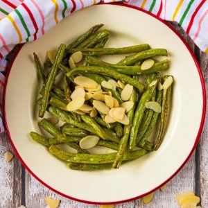 A plate of Garlic Green Beans topped with flaked almonds