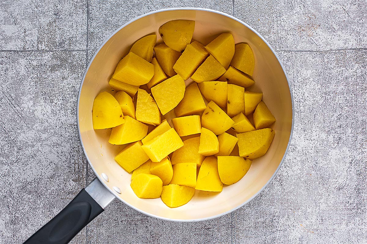 A saucepan with chopped potatoes in it.