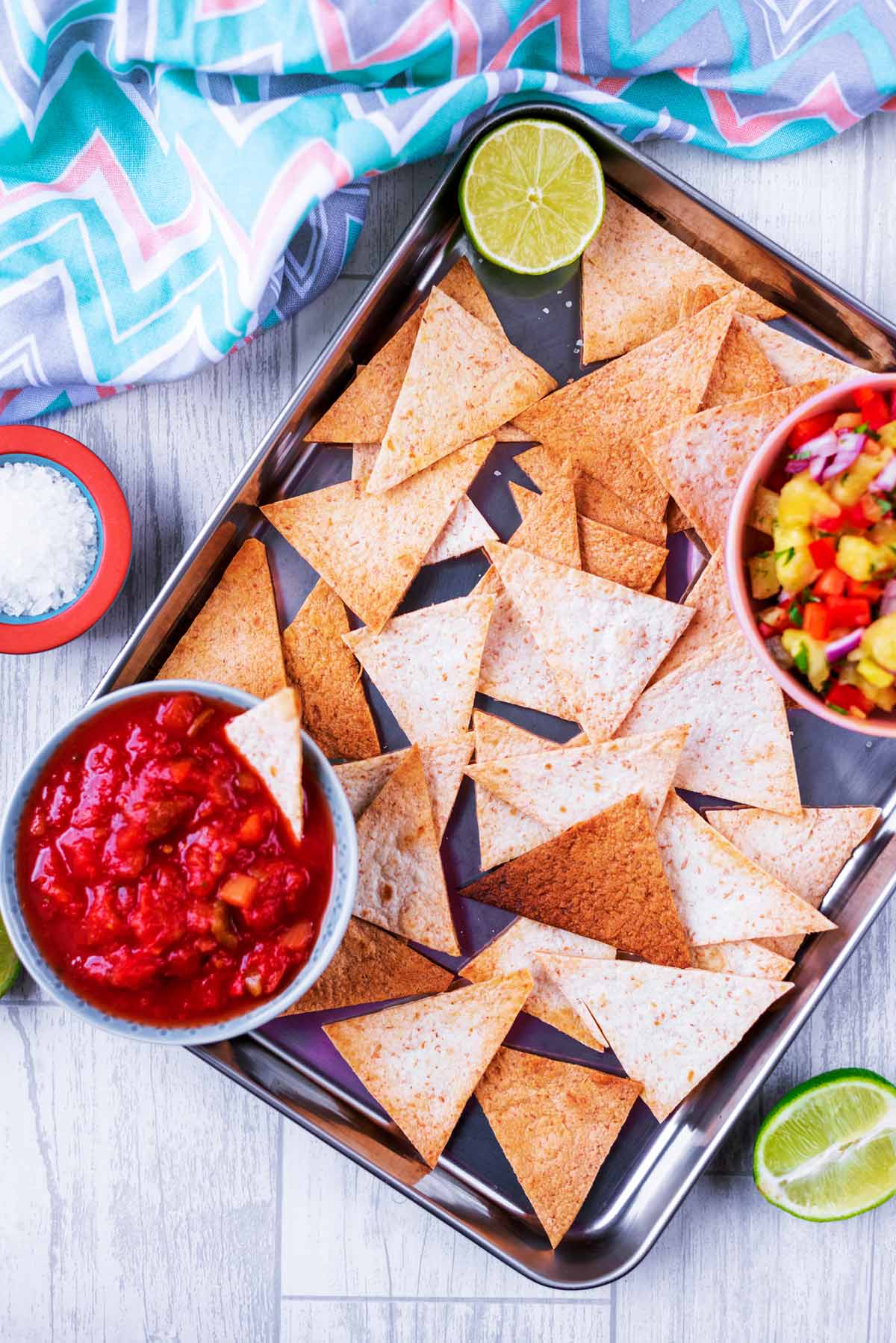 Baked Tortilla Chips on a metal tray with bowls of salsa.
