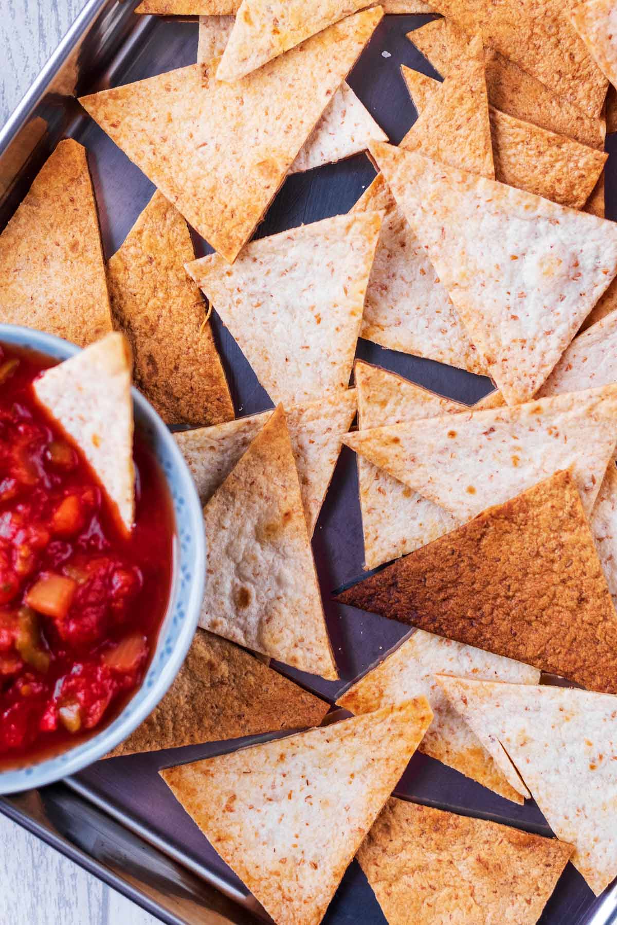 Tortilla chips next to a bowl of tomato salsa.