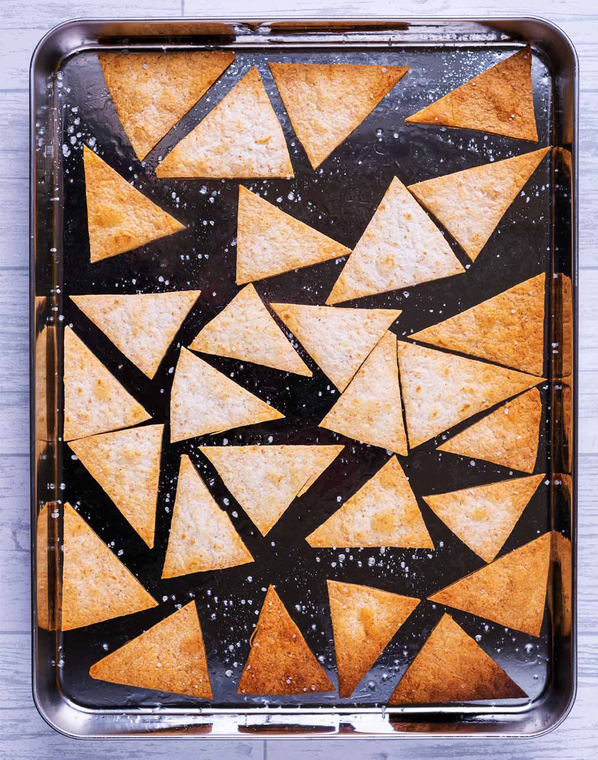 Baked tortilla chips on a baking tray.