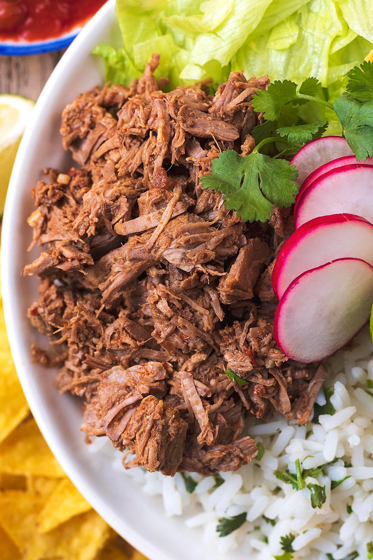 Shredded beef in a bowl with rice and salad.
