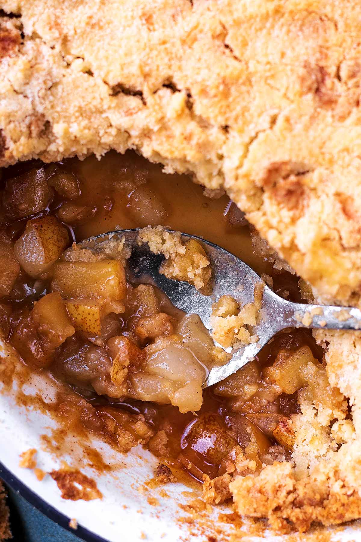 A crumble in a baking dish with a spoon in a scooped out area.