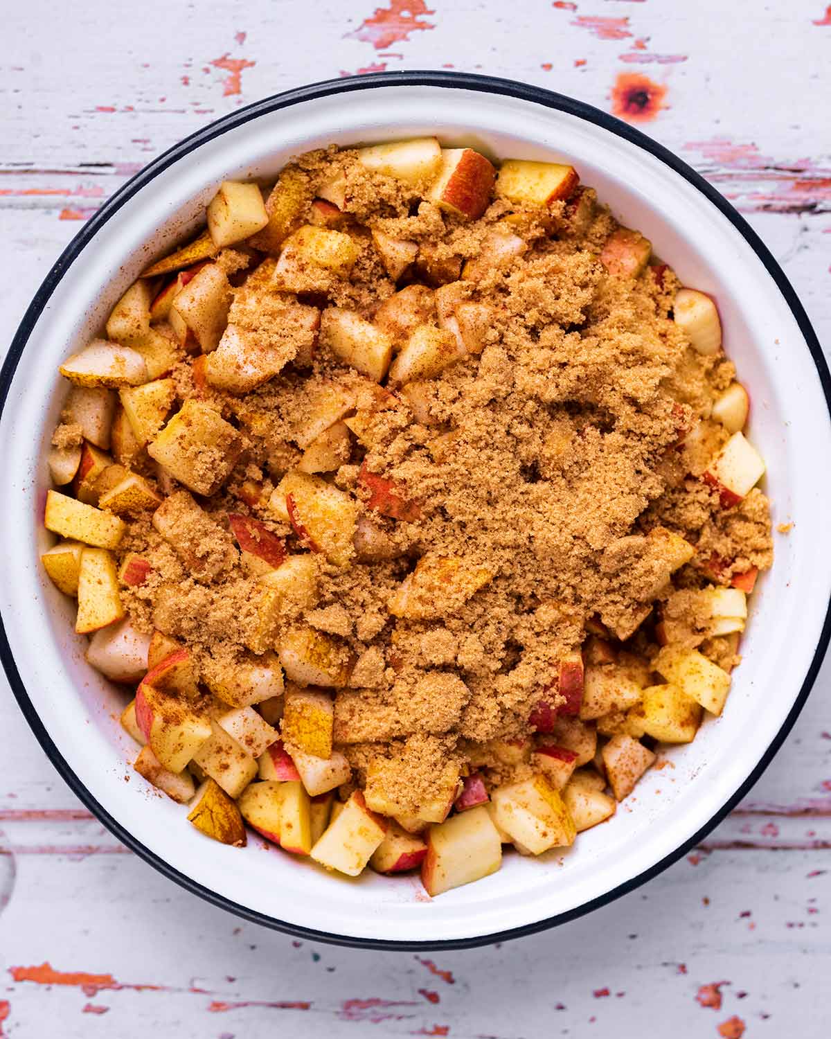 Chopped apples and pears in a baking dish with brown sugar.