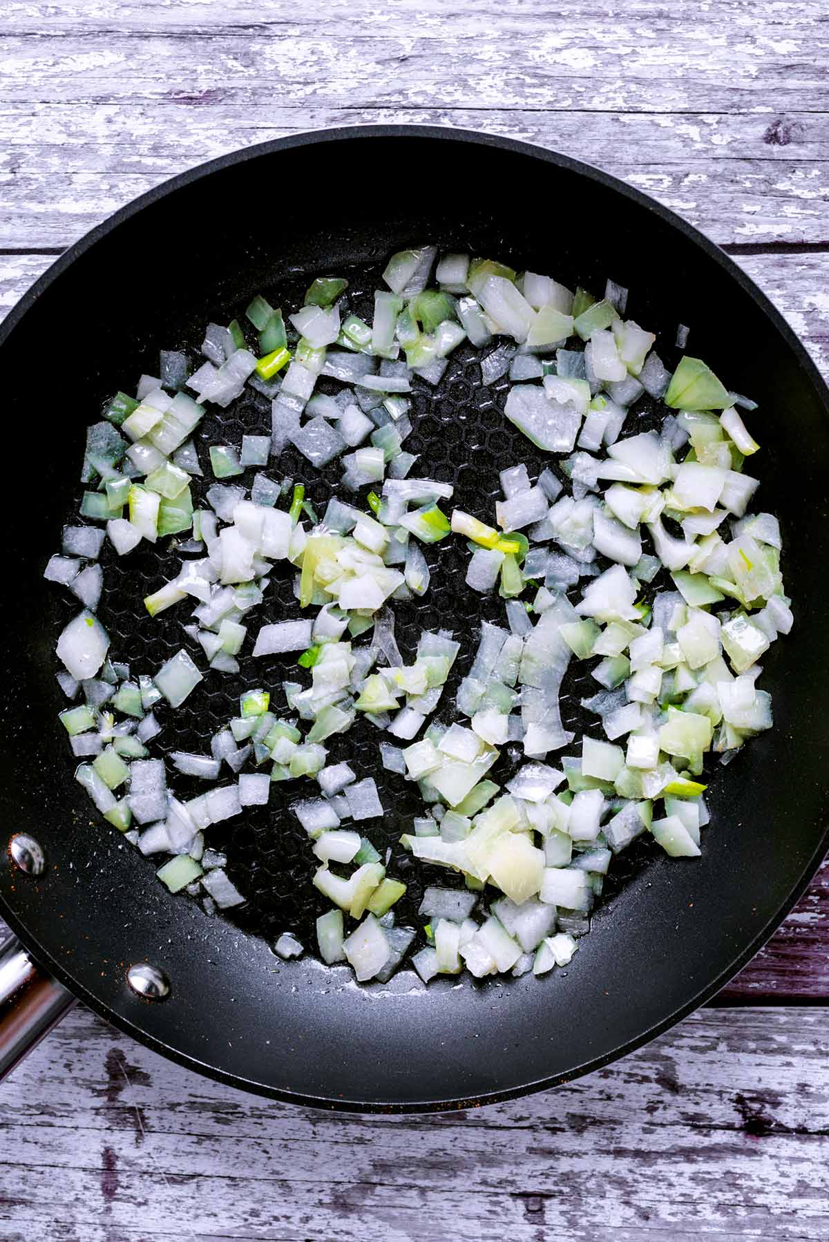 Chopped onions cooking in a frying pan.