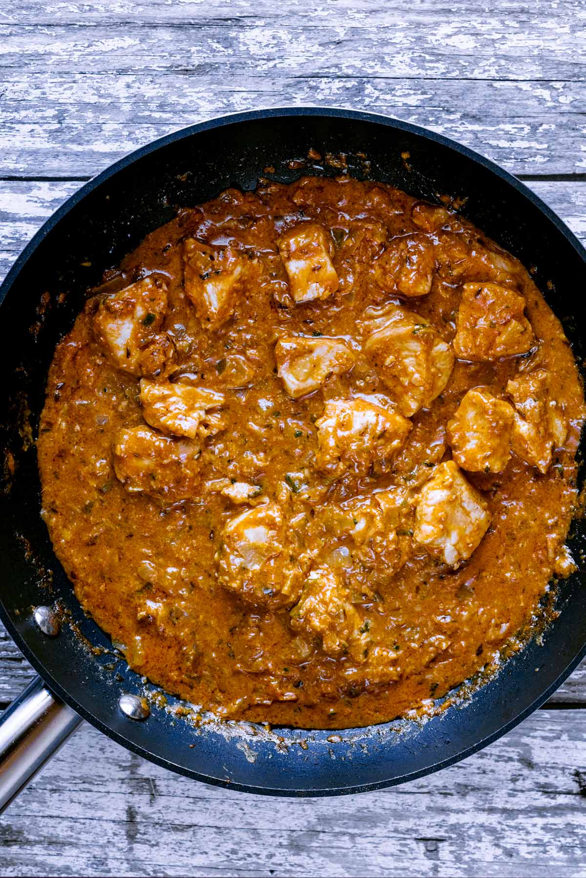 Chicken cooking in a korma sauce.