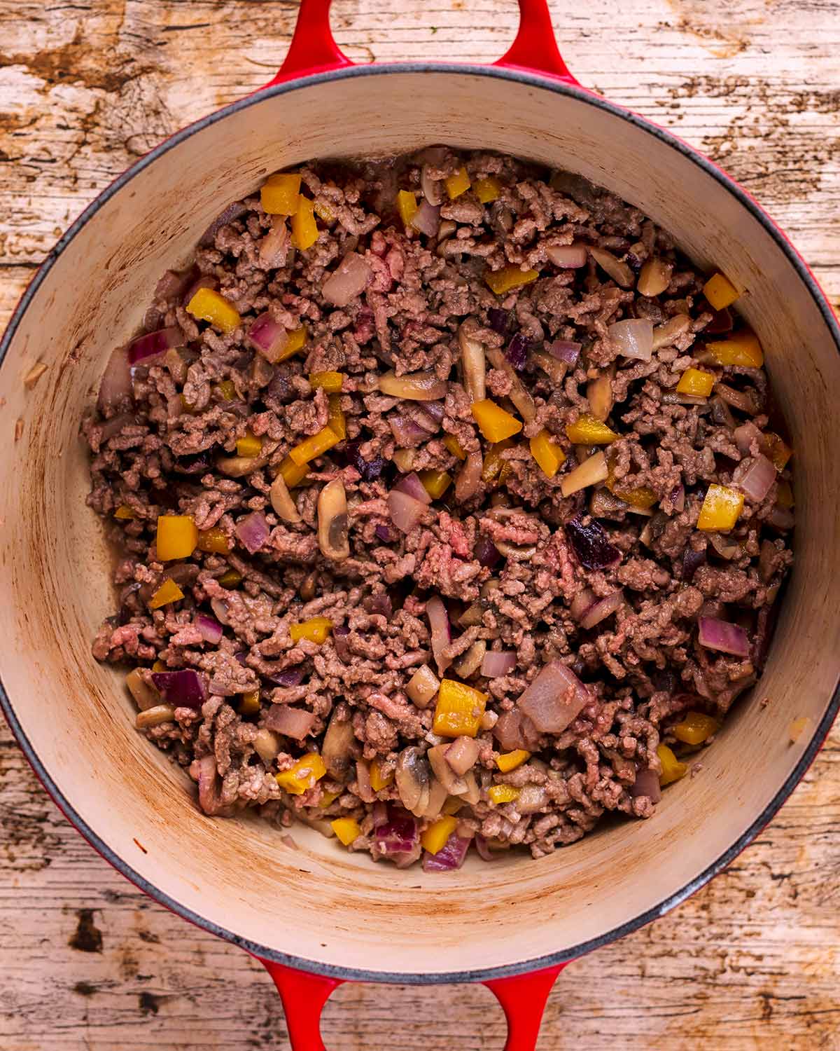 A large pot with beef mince and chopped vegetables cooking in it.
