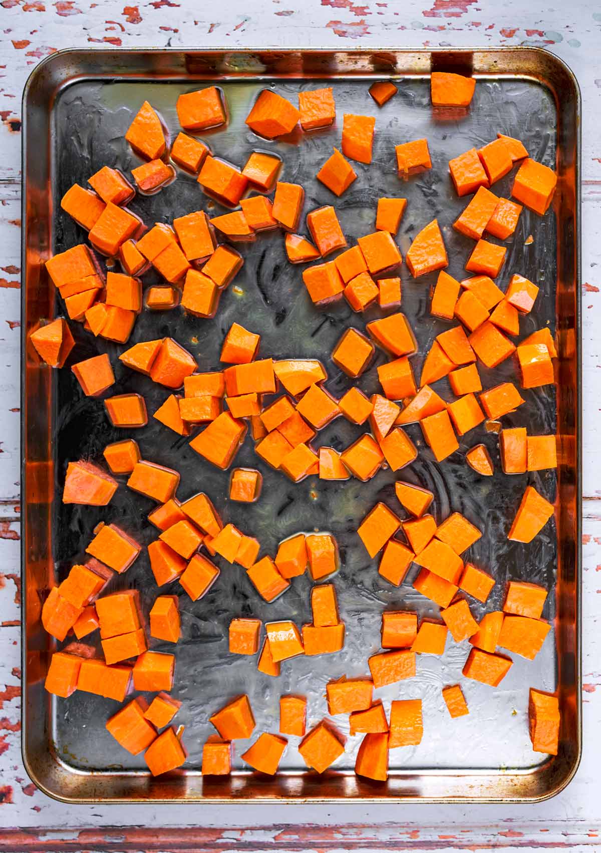 A large baking tray covered in cubes of roasted sweet potato.