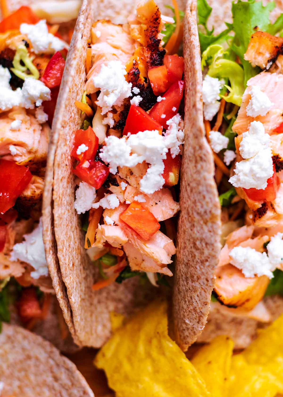 Folded tacos containing salad, salmon and feta cheese.