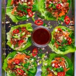 Six Asian Lettuce Wraps on a serving tray with a pot of hoisin sauce.