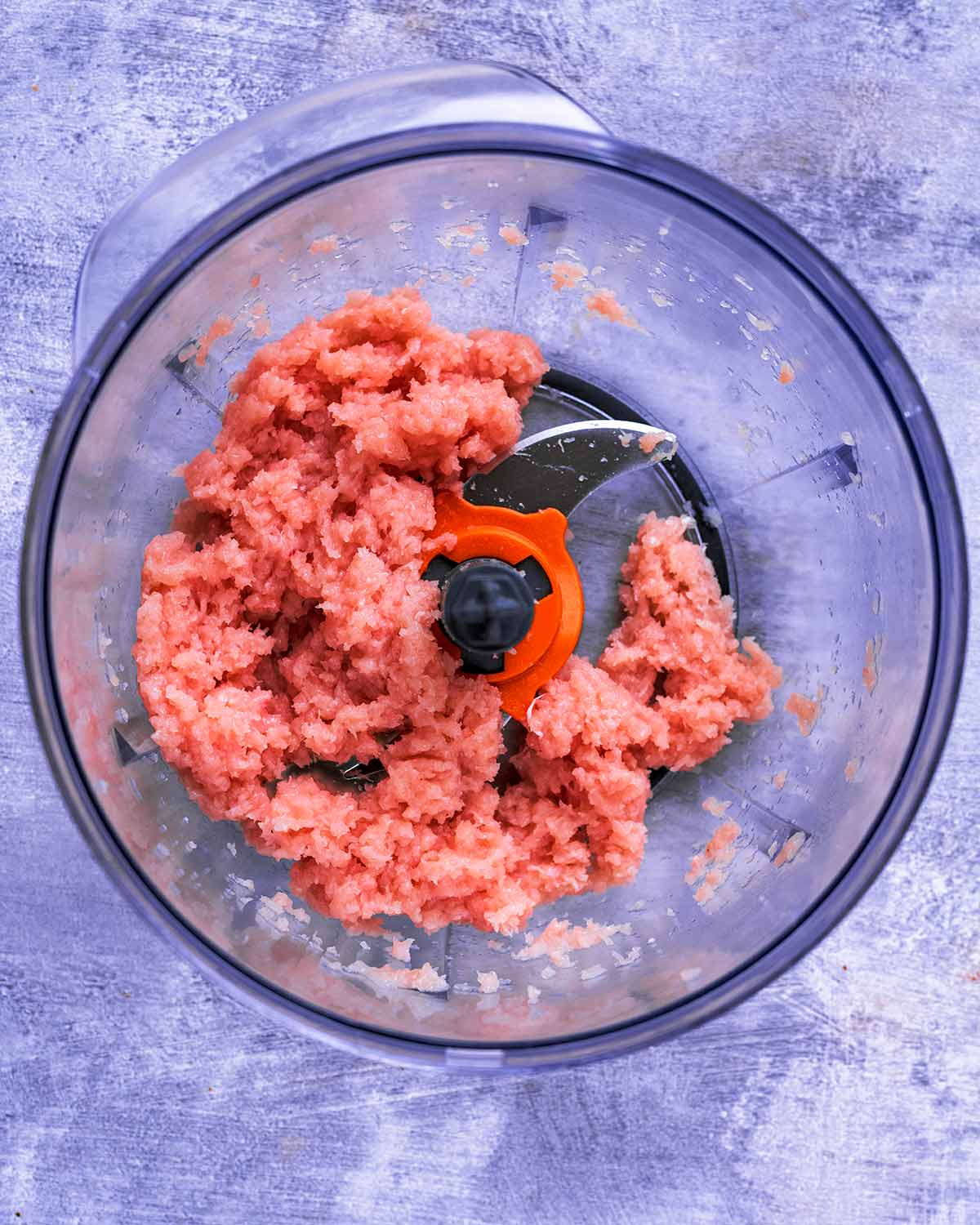 A food processor containing ground chicken.