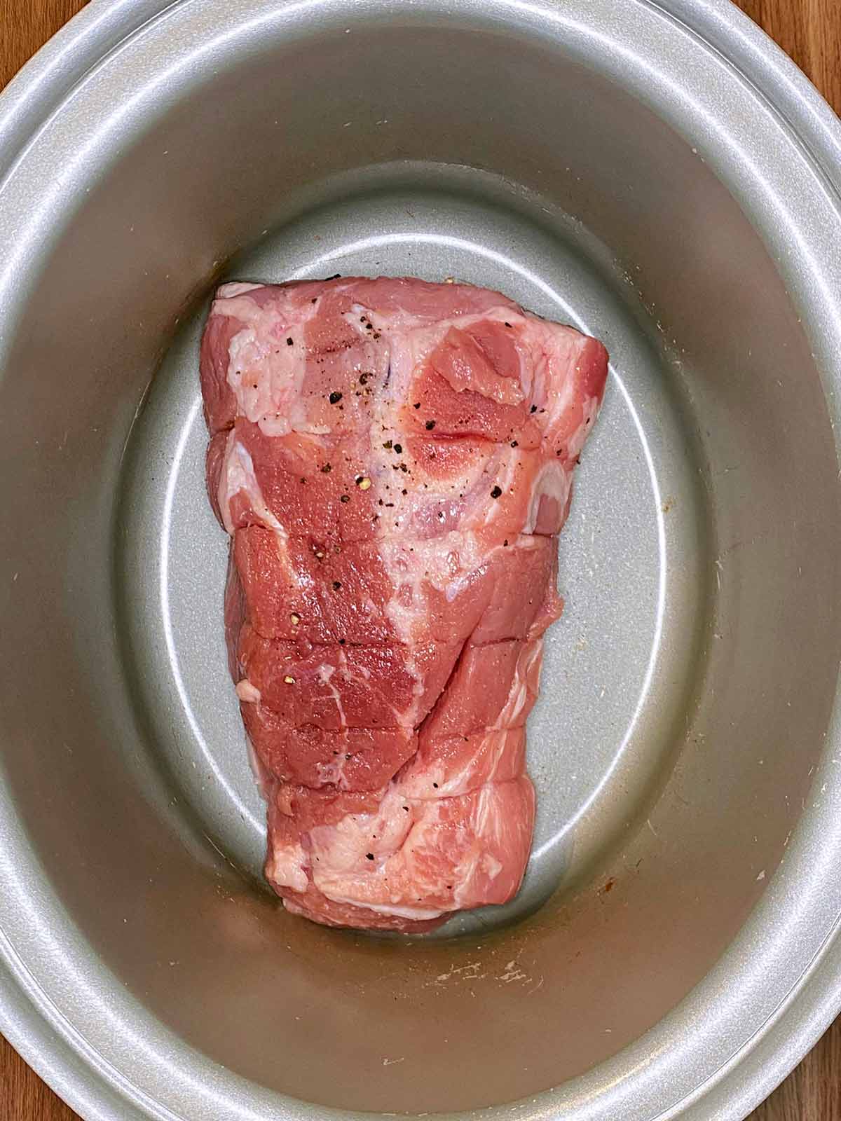 A seasoned pork joint in a slow cooker.