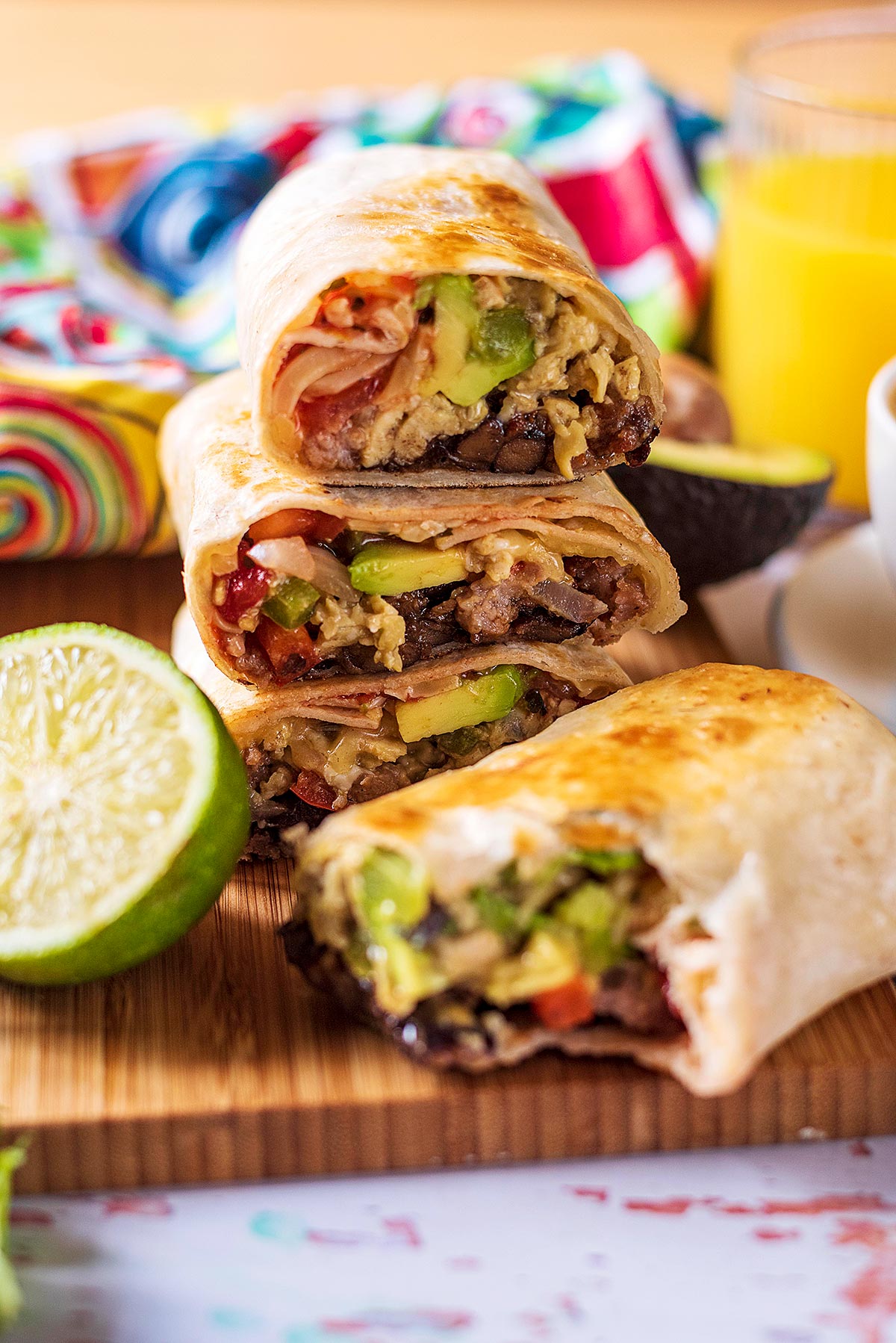 A stack of burritos on a wooden surface.