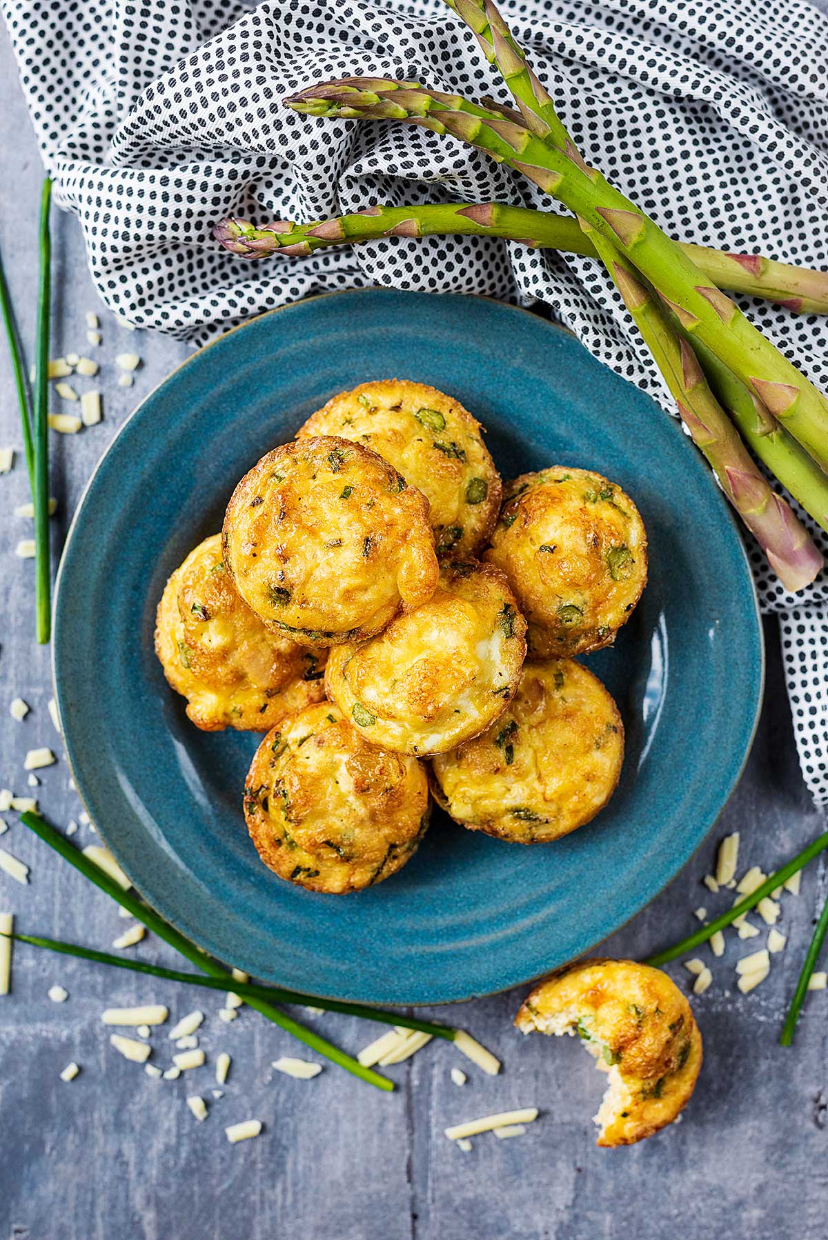 A plate of egg muffins next to some asparagus spears.