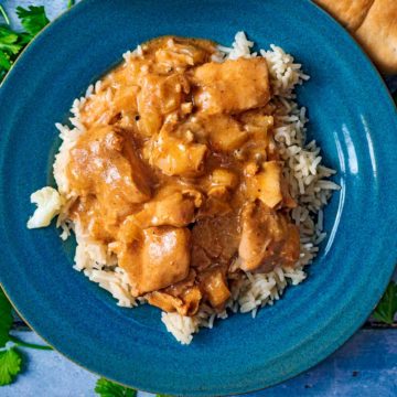 A plate of slow cooker butter chicken on a bed of rice.