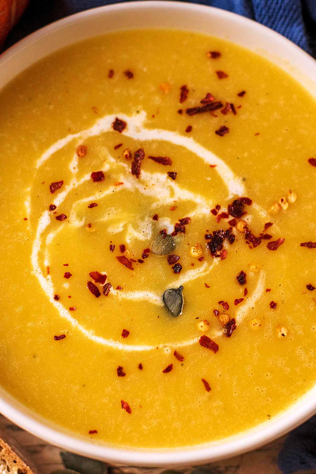 Pumpkin seeds, chilli flakes and a drizzle of cream on top of pumpkin soup.