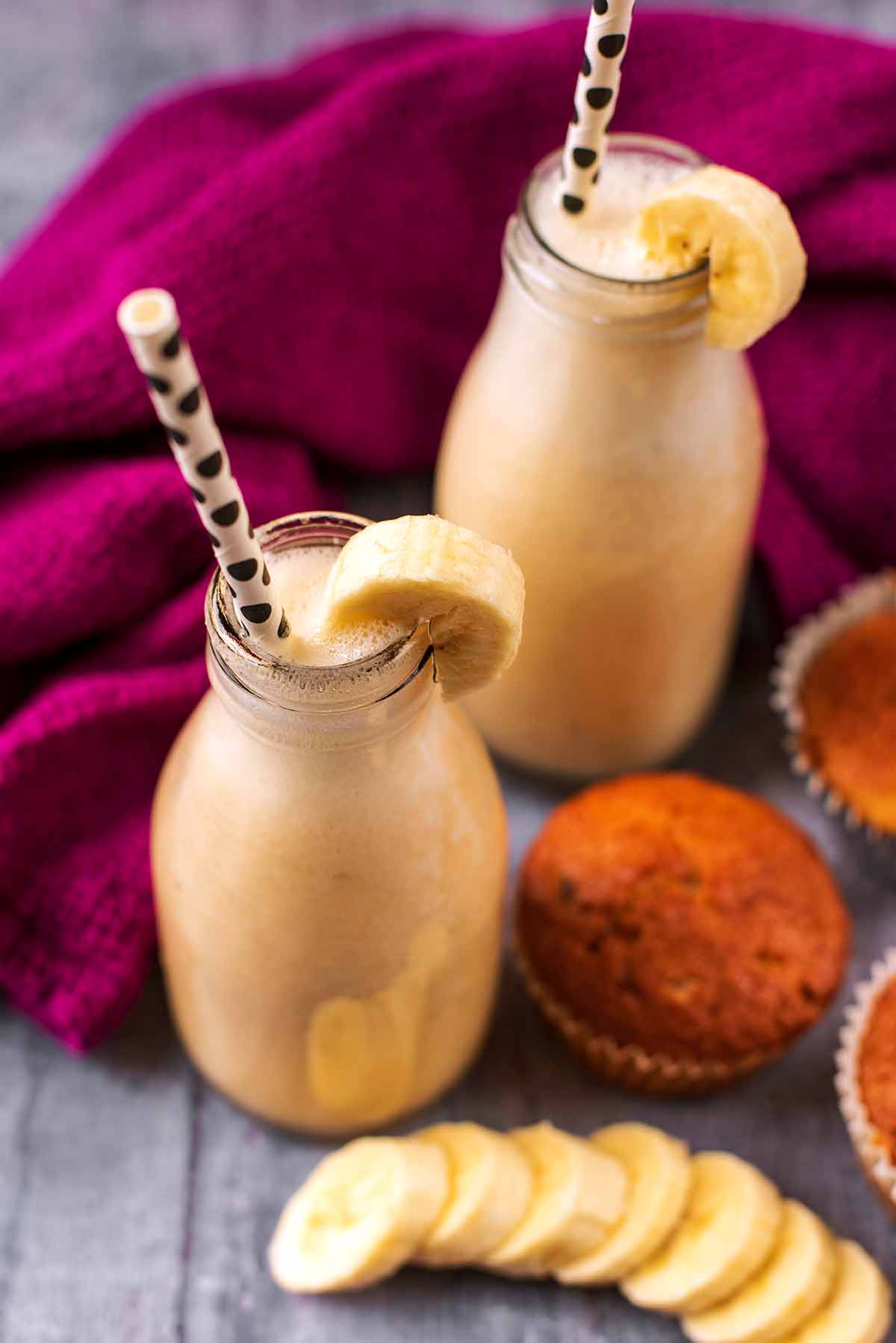 Banana milk in bottles next to some muffins.