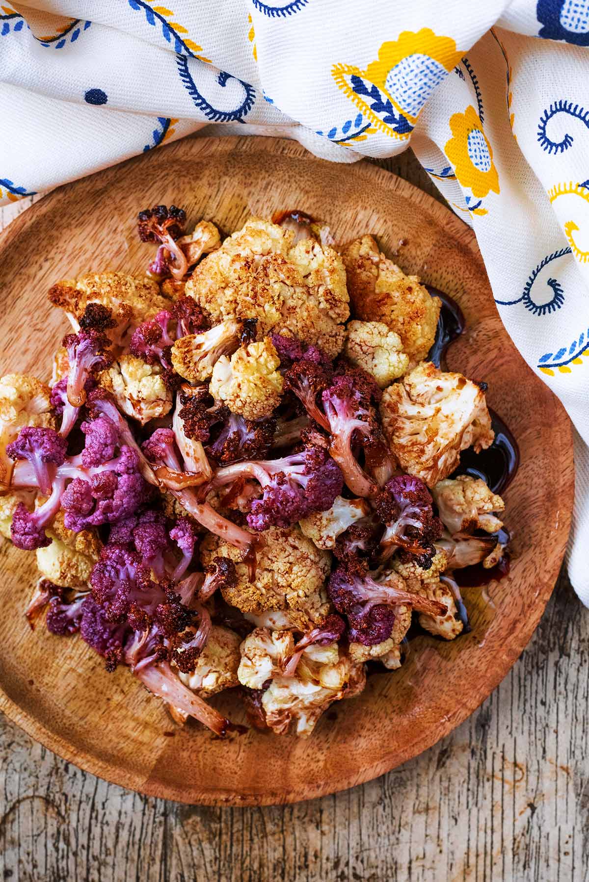 A plate of roasted cauliflower next to a patterned towel.