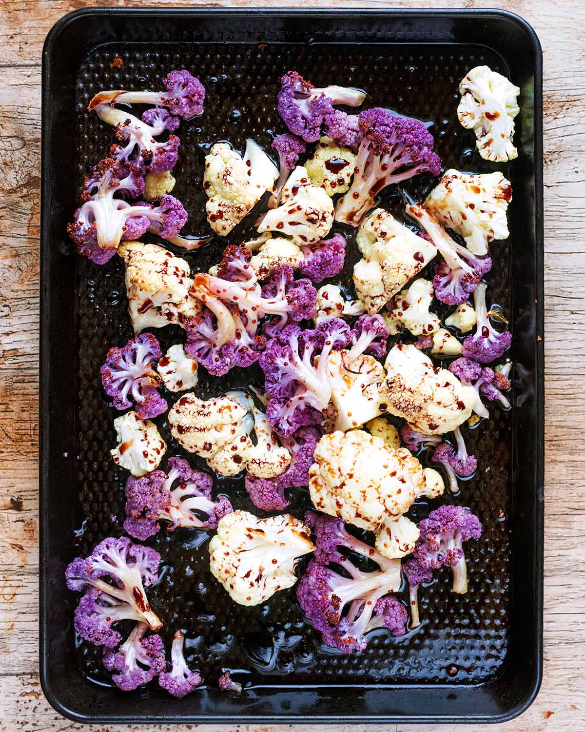 Oil, balsamic vinegar and seasoning poured over the cauliflower.