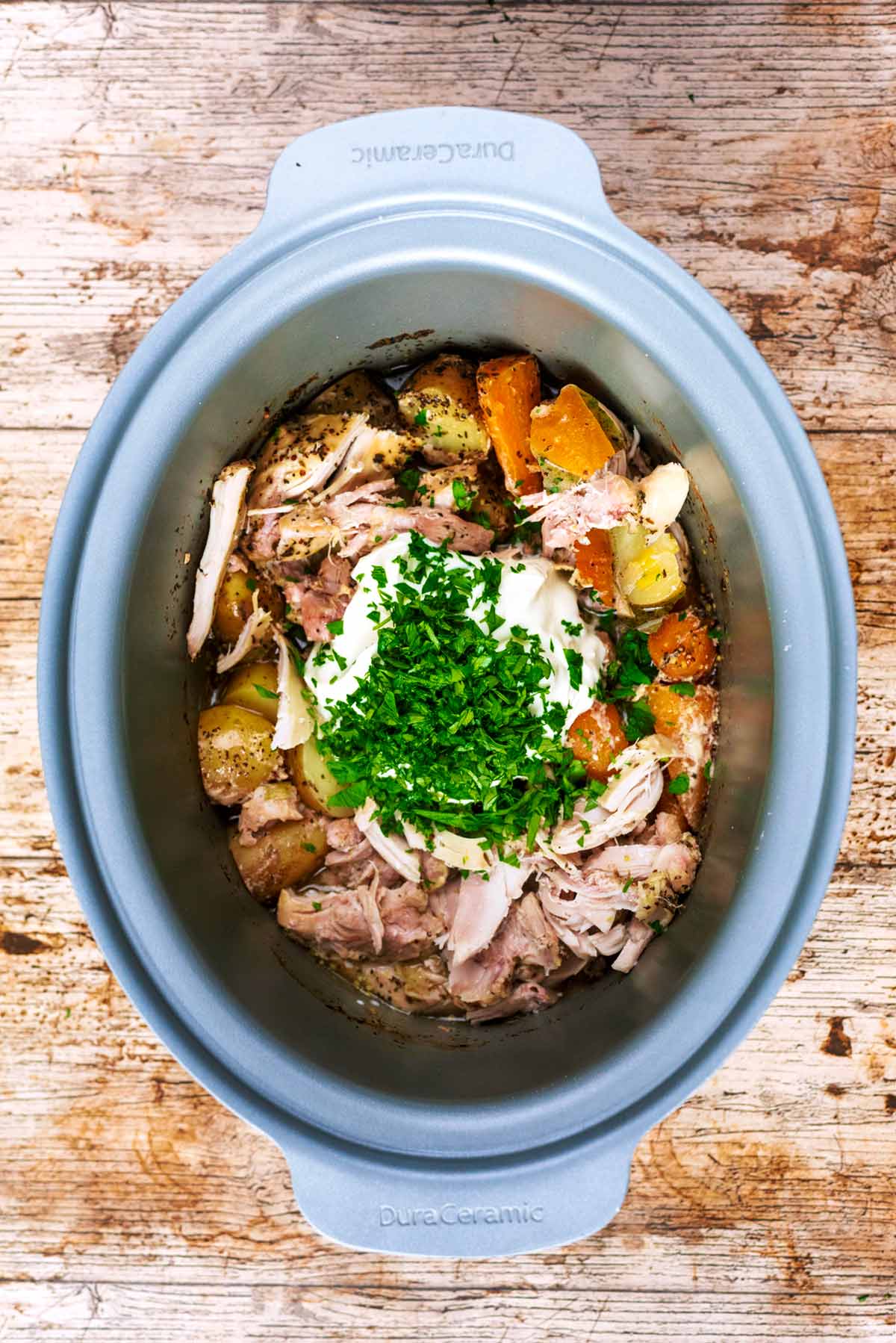 Shredded chicken, vegetables, cream and herbs in a slow cooker.