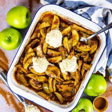 A large baking tray full of baked apples topped with three scoops of ice cream.