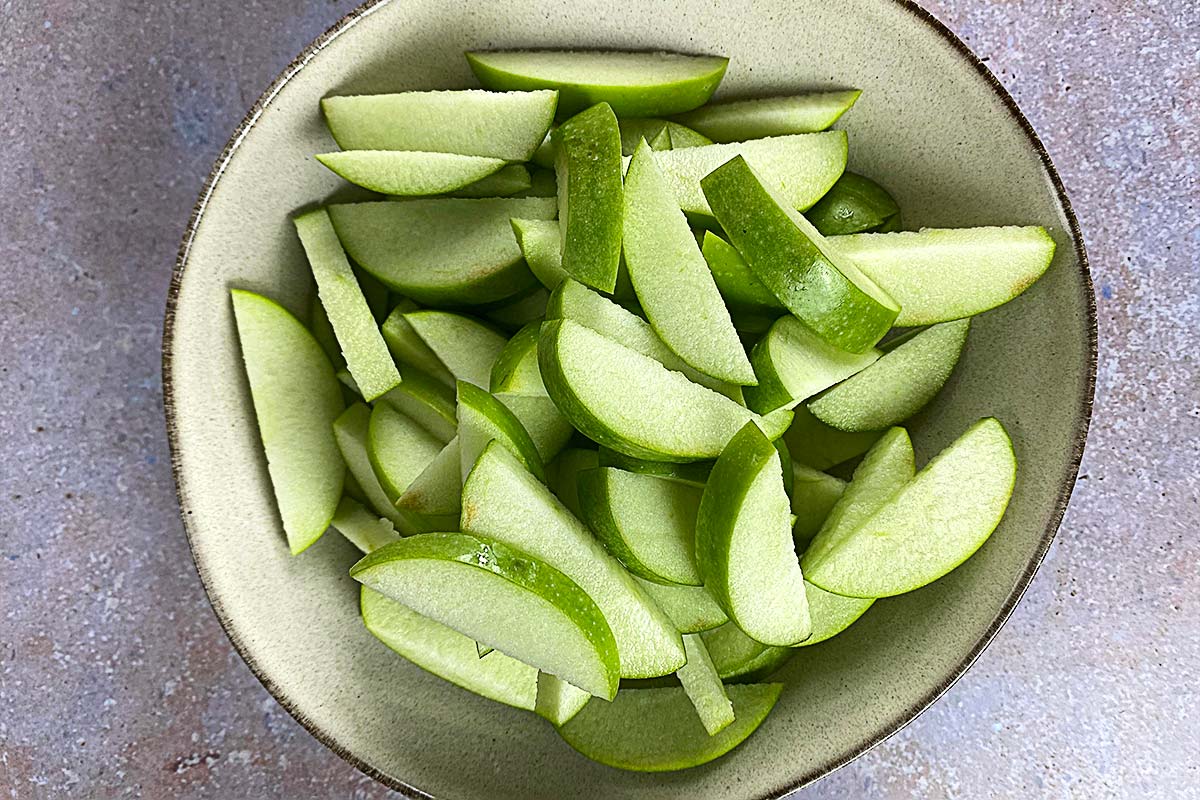 A bowl of sliced green apples.