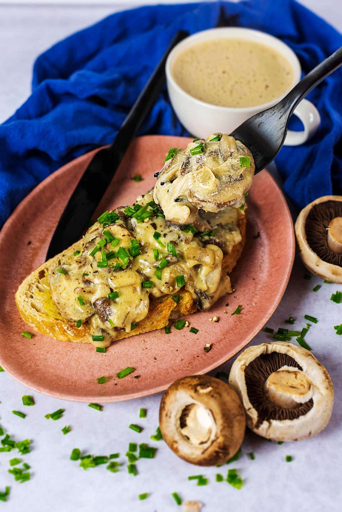 A fork picking up some creamy mushrooms from a plate.