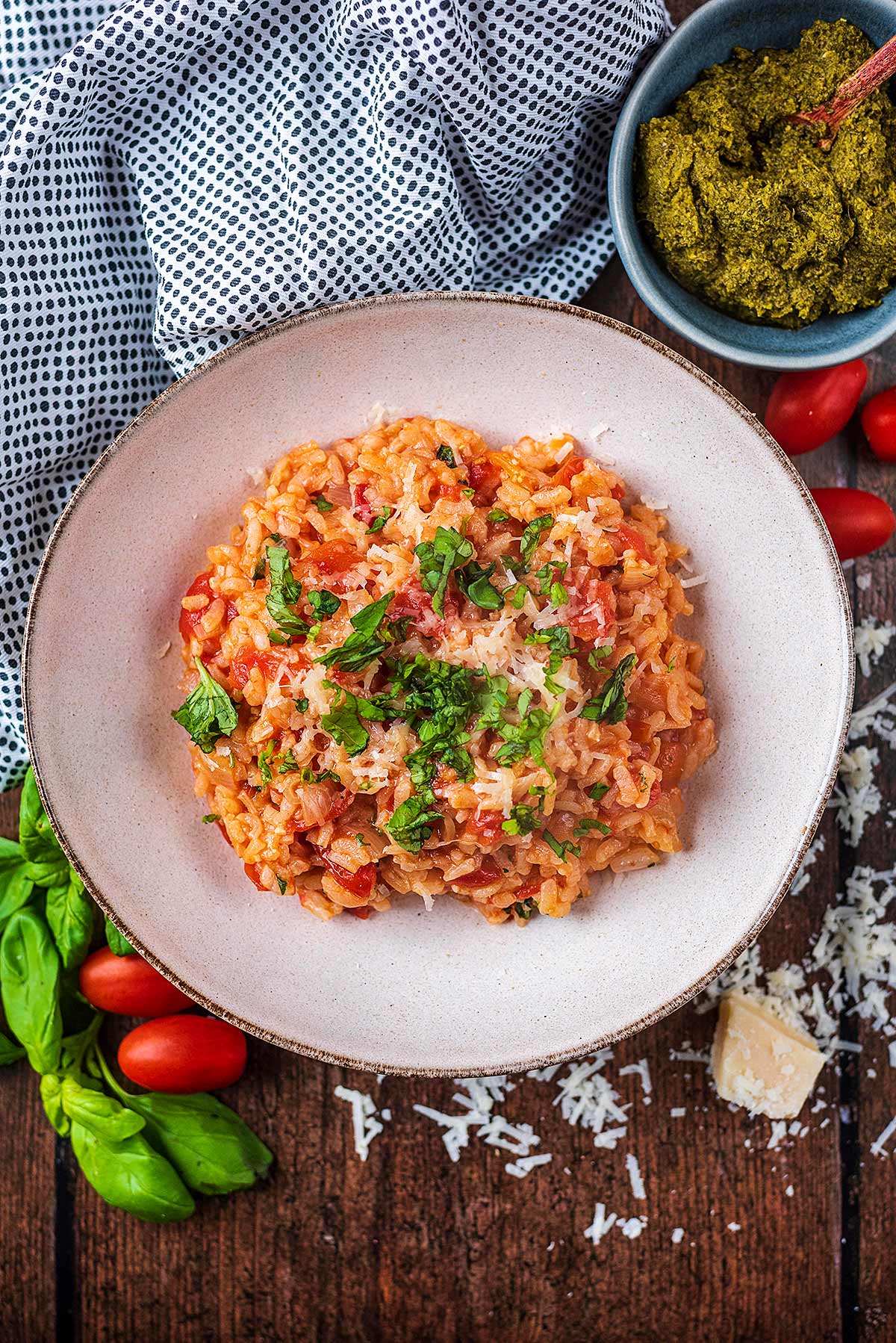 Tomato risotto in a large bowl next to a bowl of pesto.
