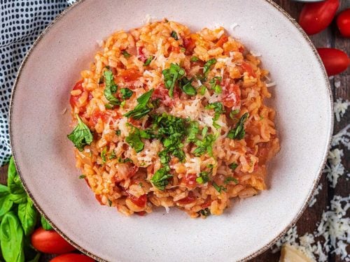 Easy Tomato Baked Risotto in a large bowl topped with chopped herbs.