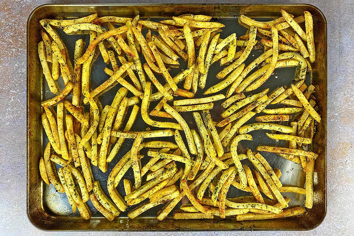 A baking sheet covered in seasoned fries.