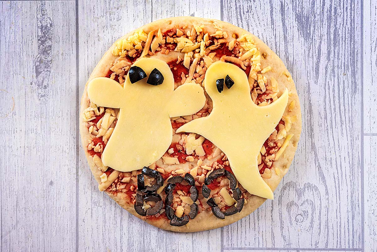 A pizza with two ghosts cut out of cheese on top.