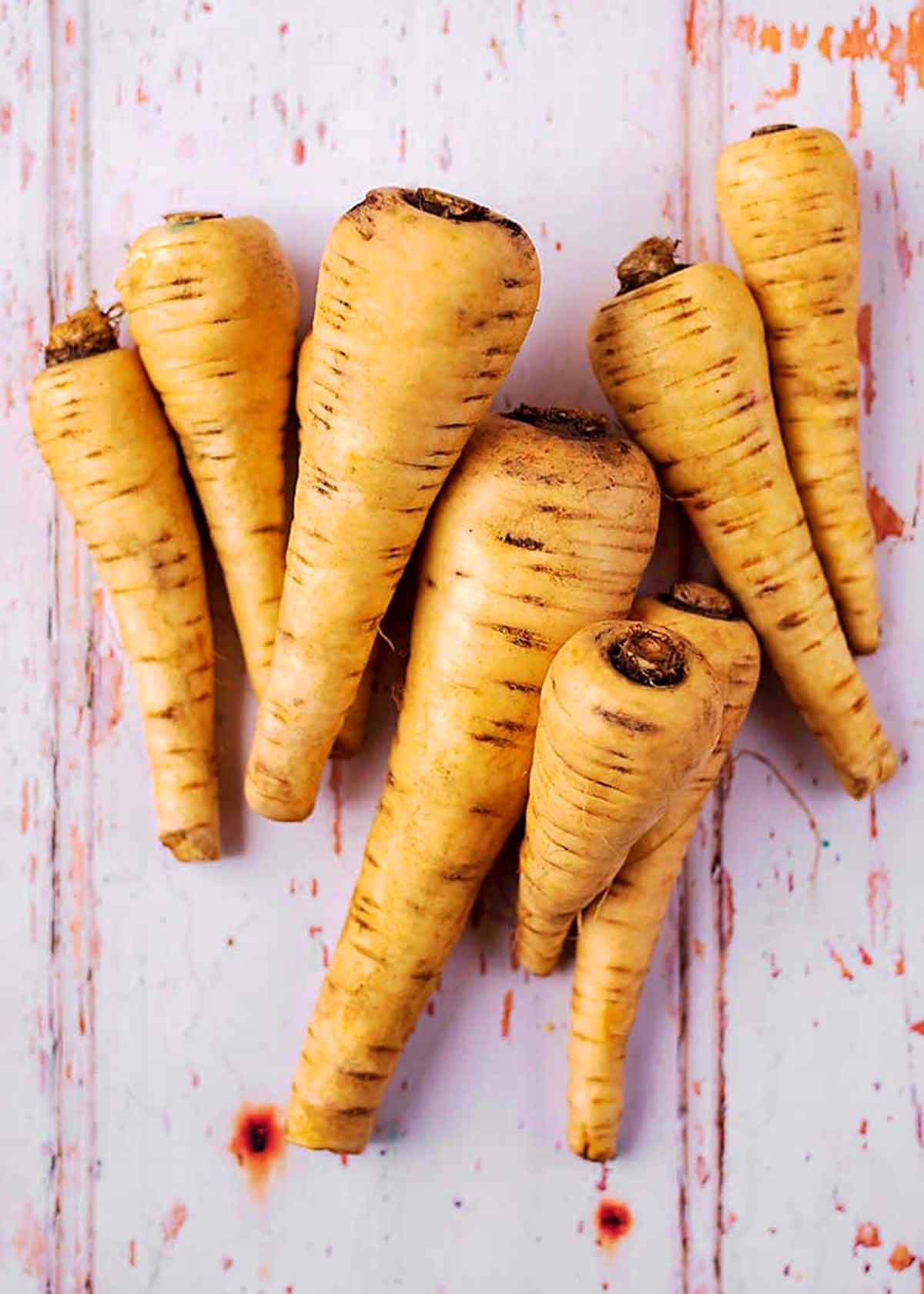 Eight parsnips on a wooden surface.