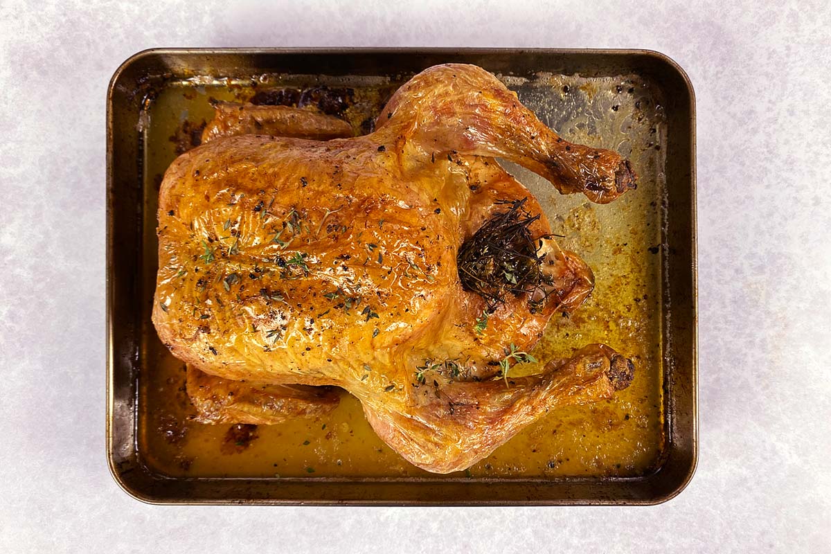 A whole roasted chicken on a baking tray.