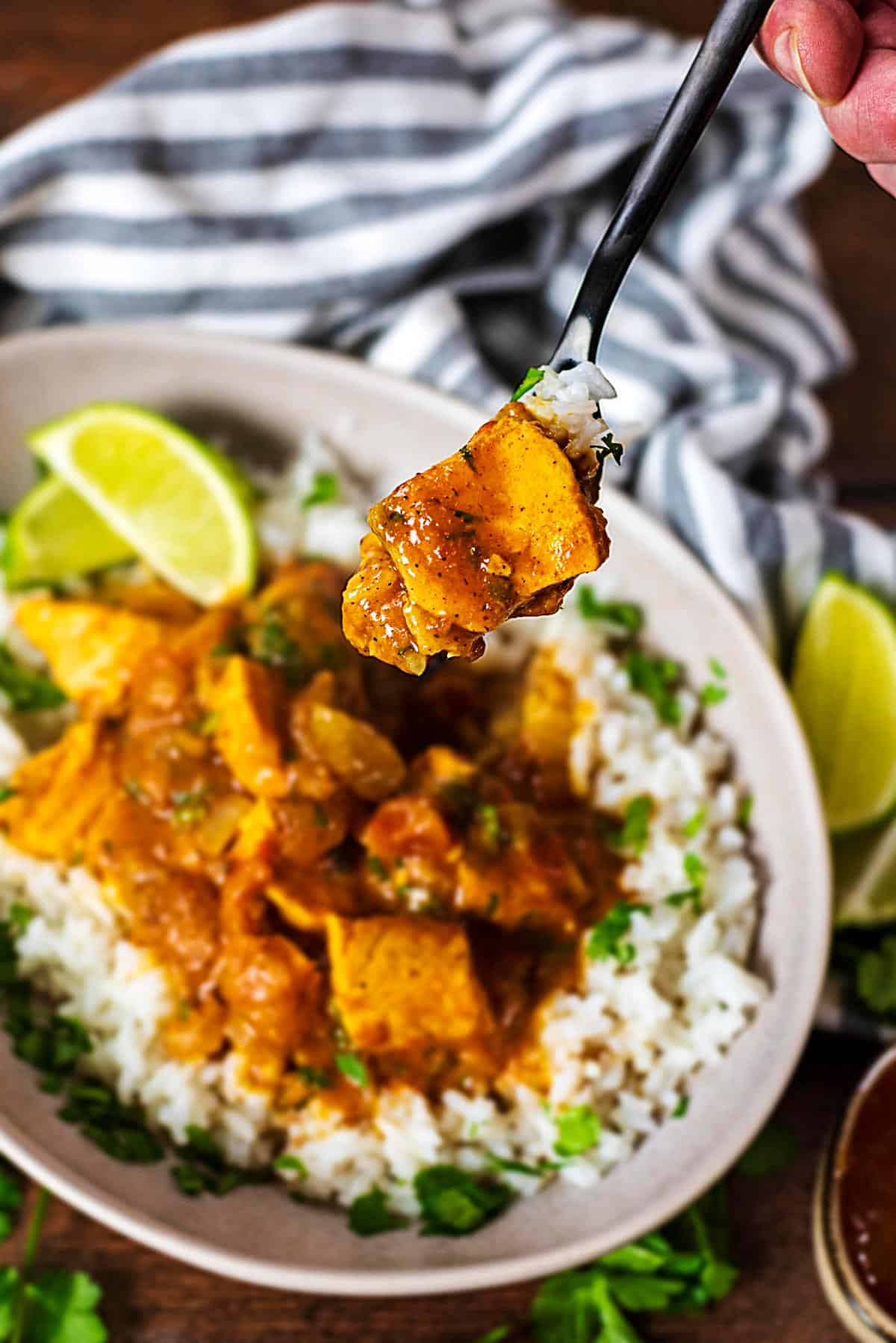 A fork picking out a piece of salmon from a curry dish.