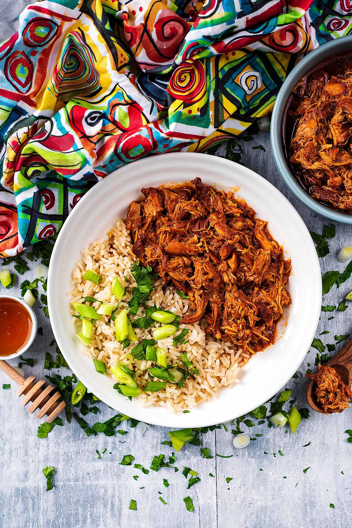 A plate of shredded chicken and rice next to a colourful towel.