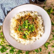 Slow cooker teriyaki chicken on a bed of rice topped with chopped spring onions.