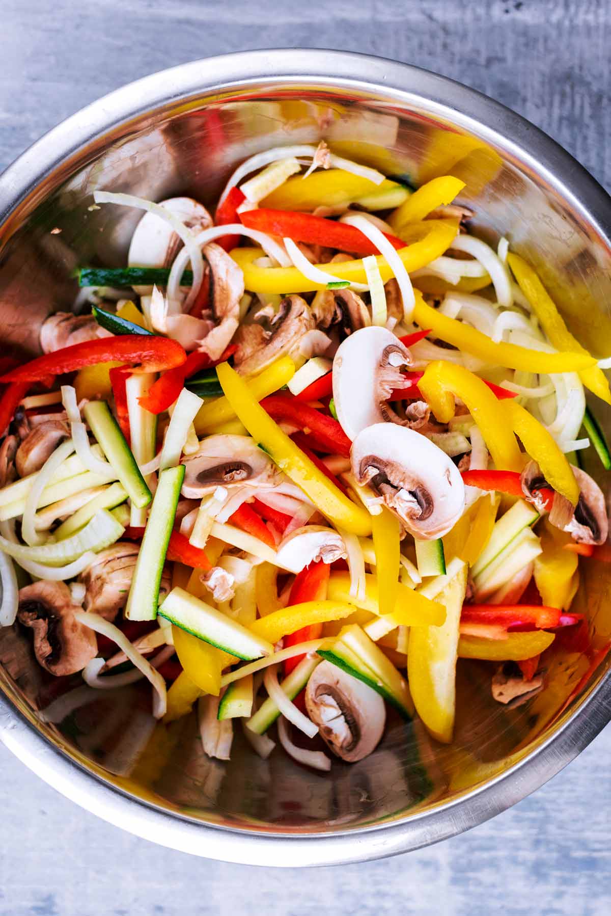 A large metal bowl full of sliced vegetables.