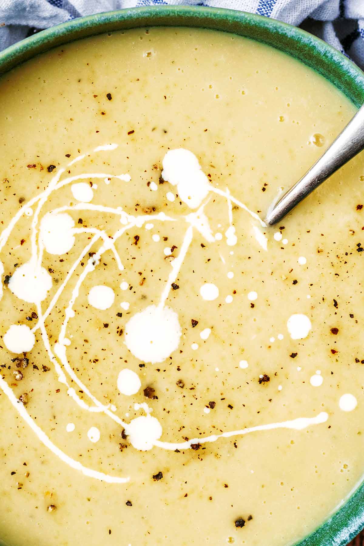 Cream drizzles over a bowl of parsnip soup.