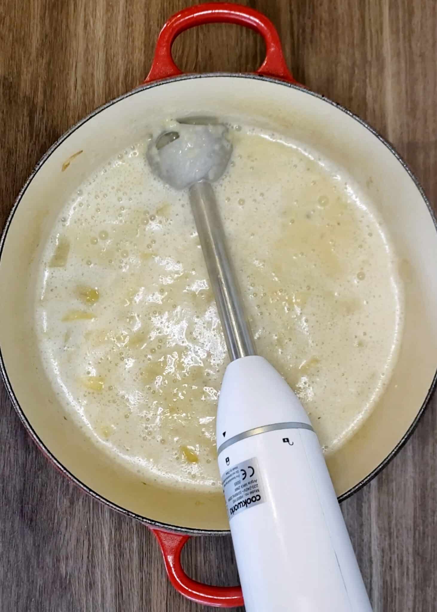 Blended soup in a pan with a stick blender.