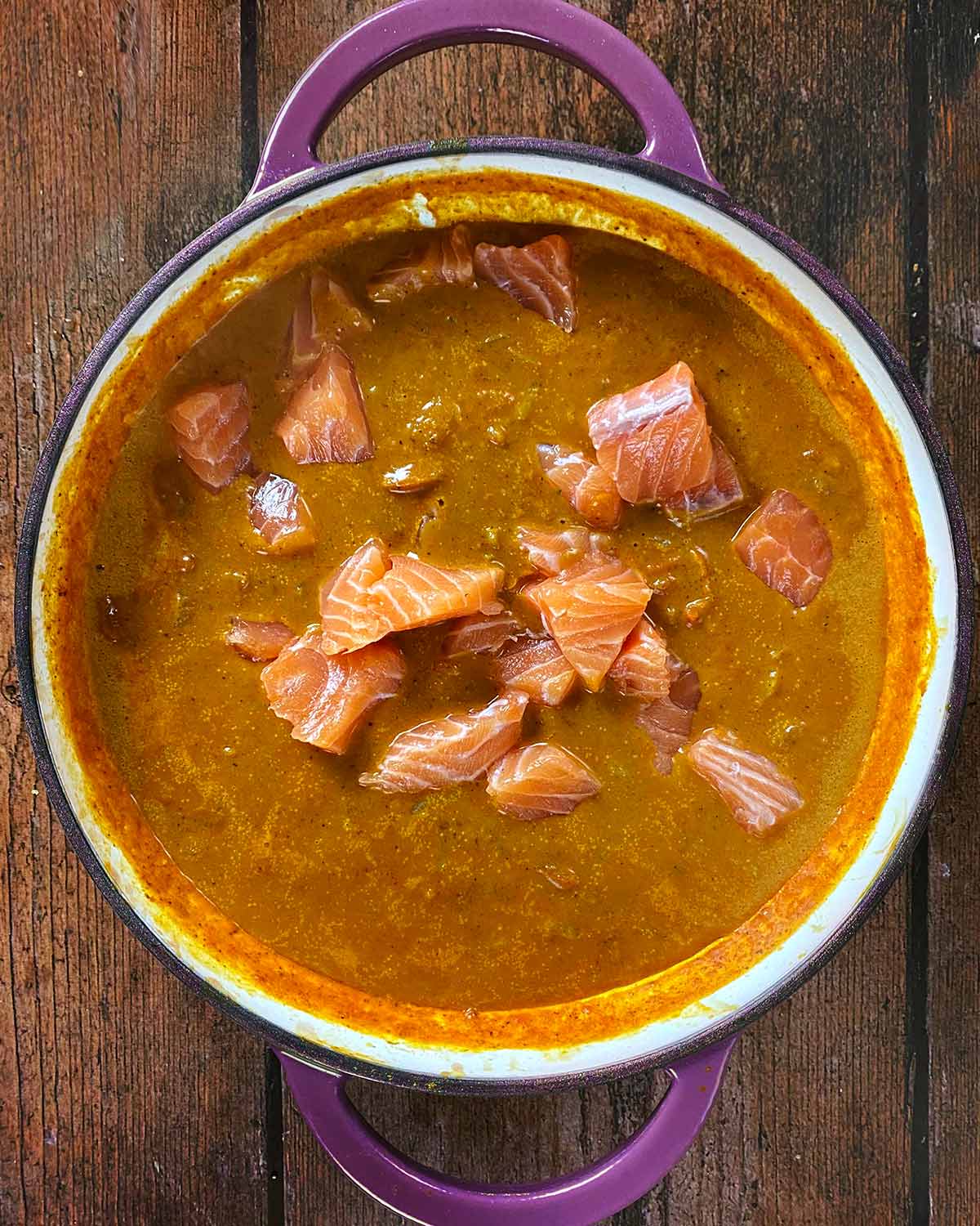 Raw salmon chunks in a curry sauce.