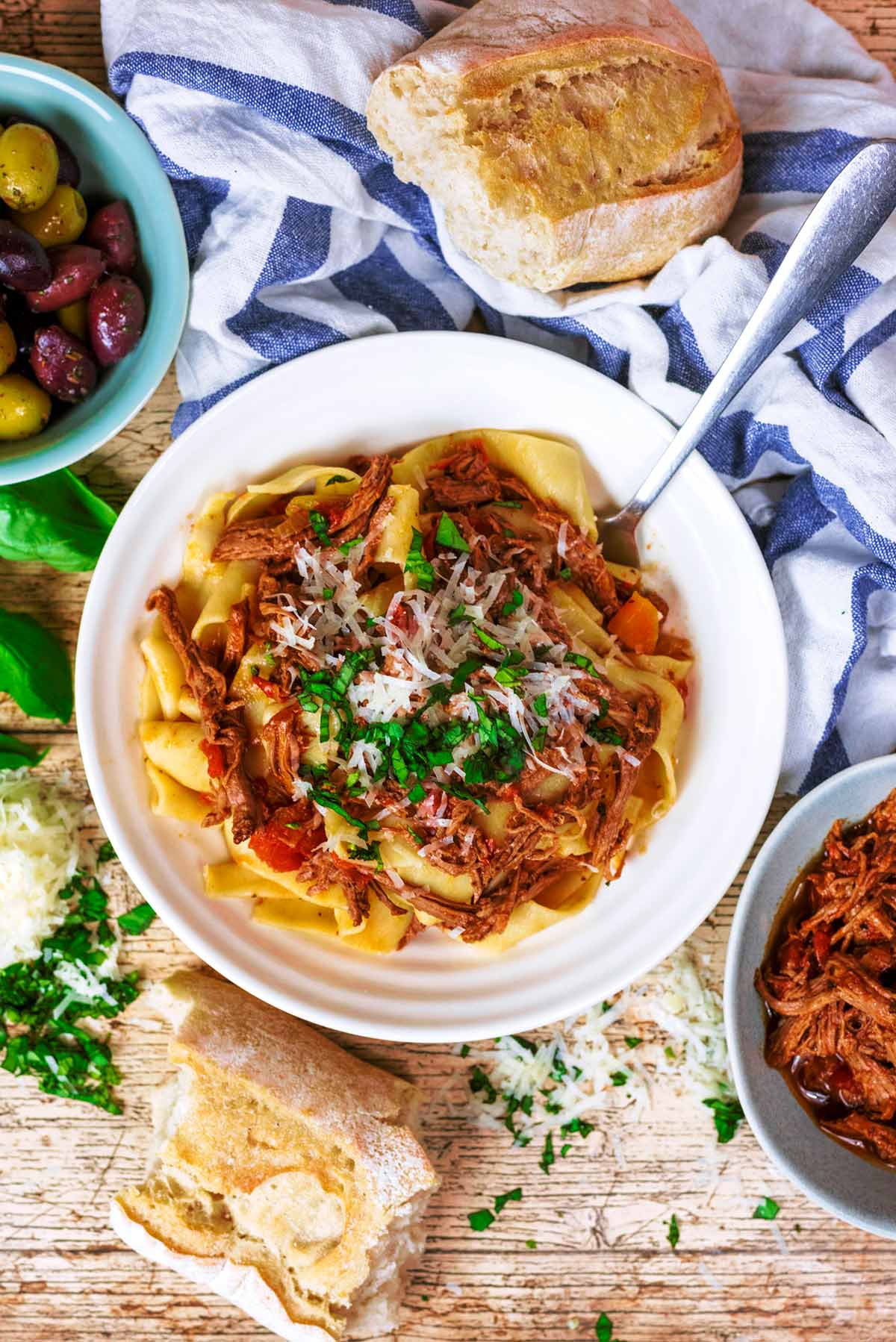 Pappardelle pasta mixed with a beef sauce, topped with grated cheese and chopped herbs.