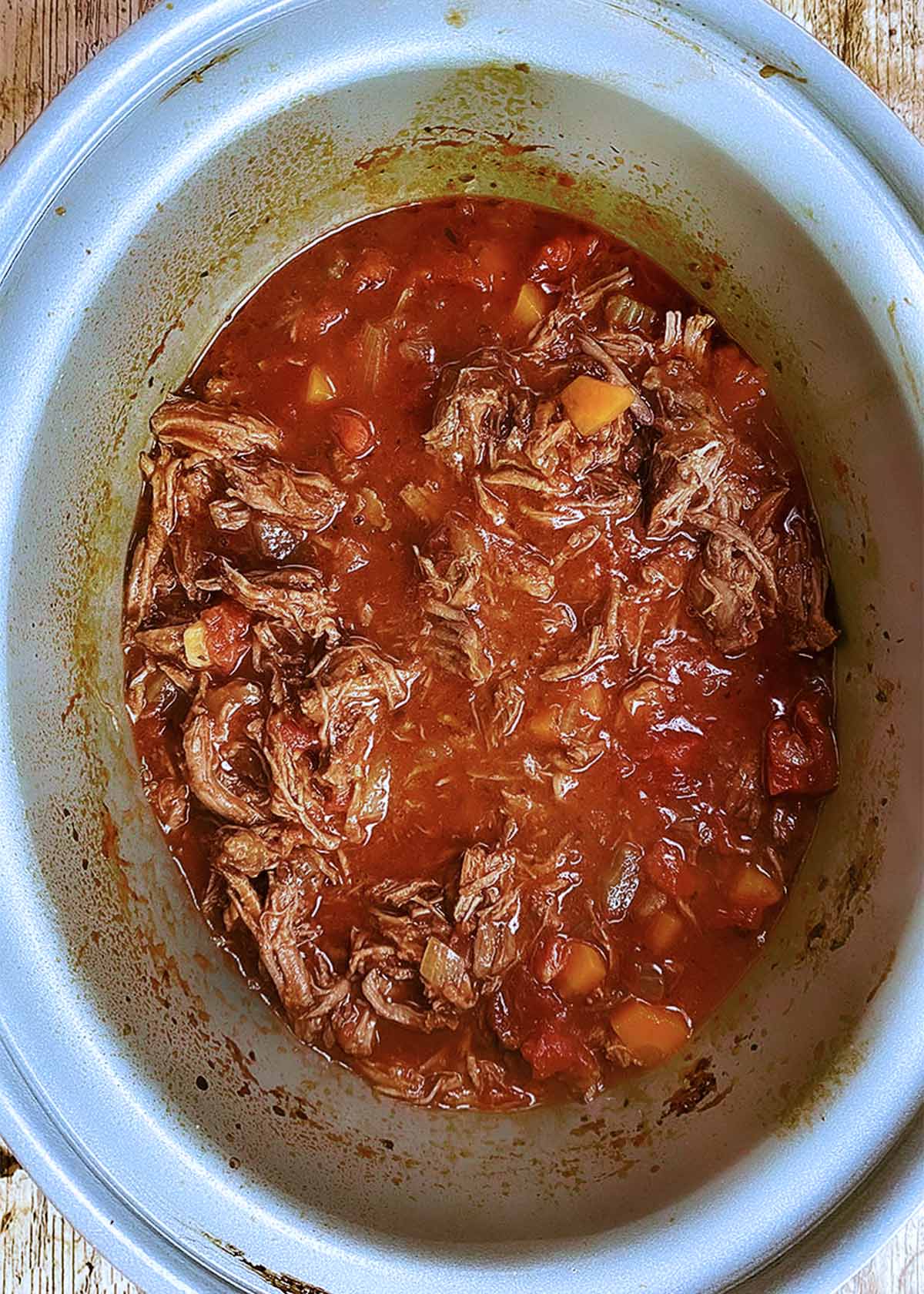 Shredded beef back in the sauce in the slow cooker.