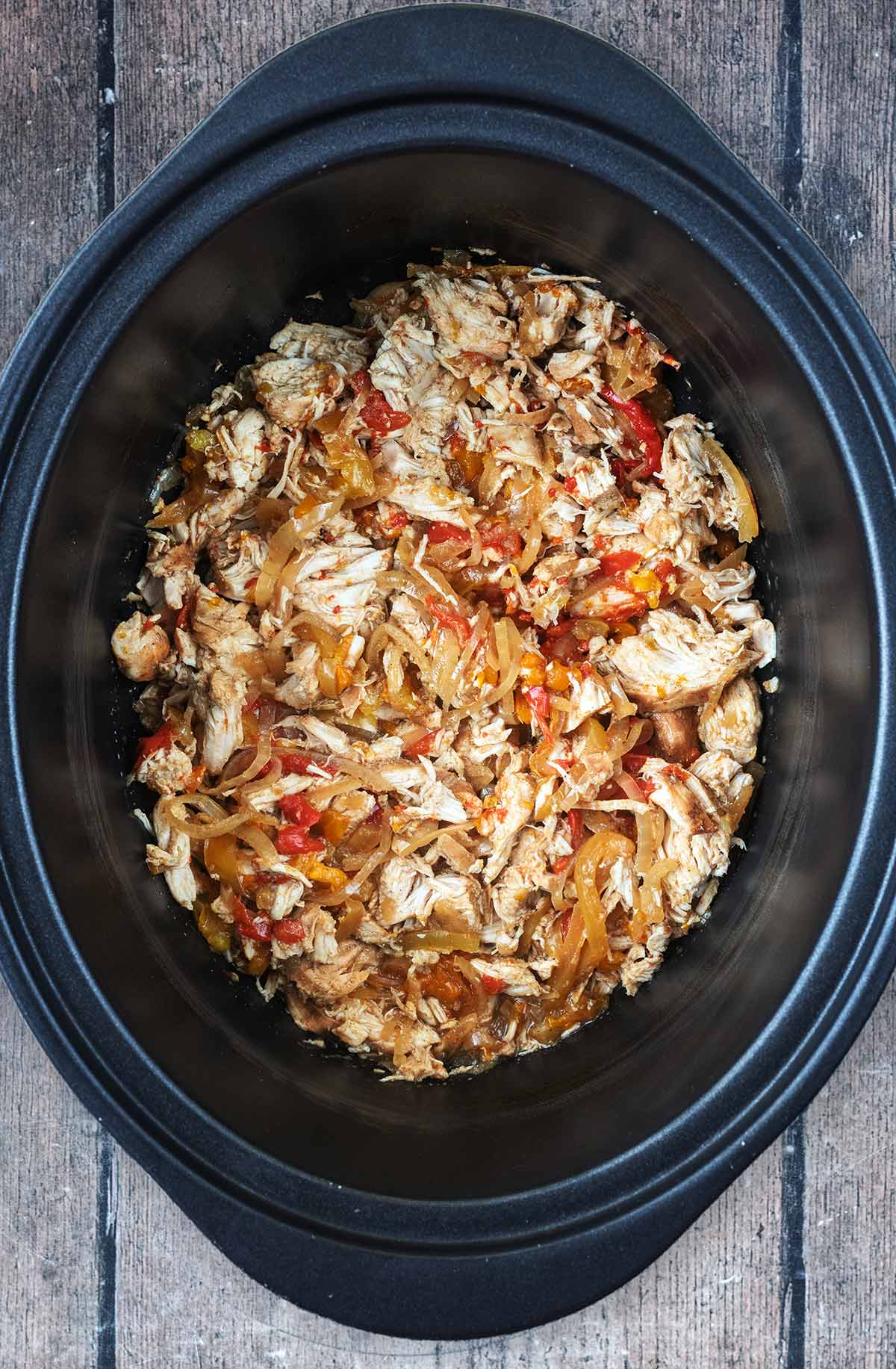 A slow cooker bowl full of chicken fajita mixture.