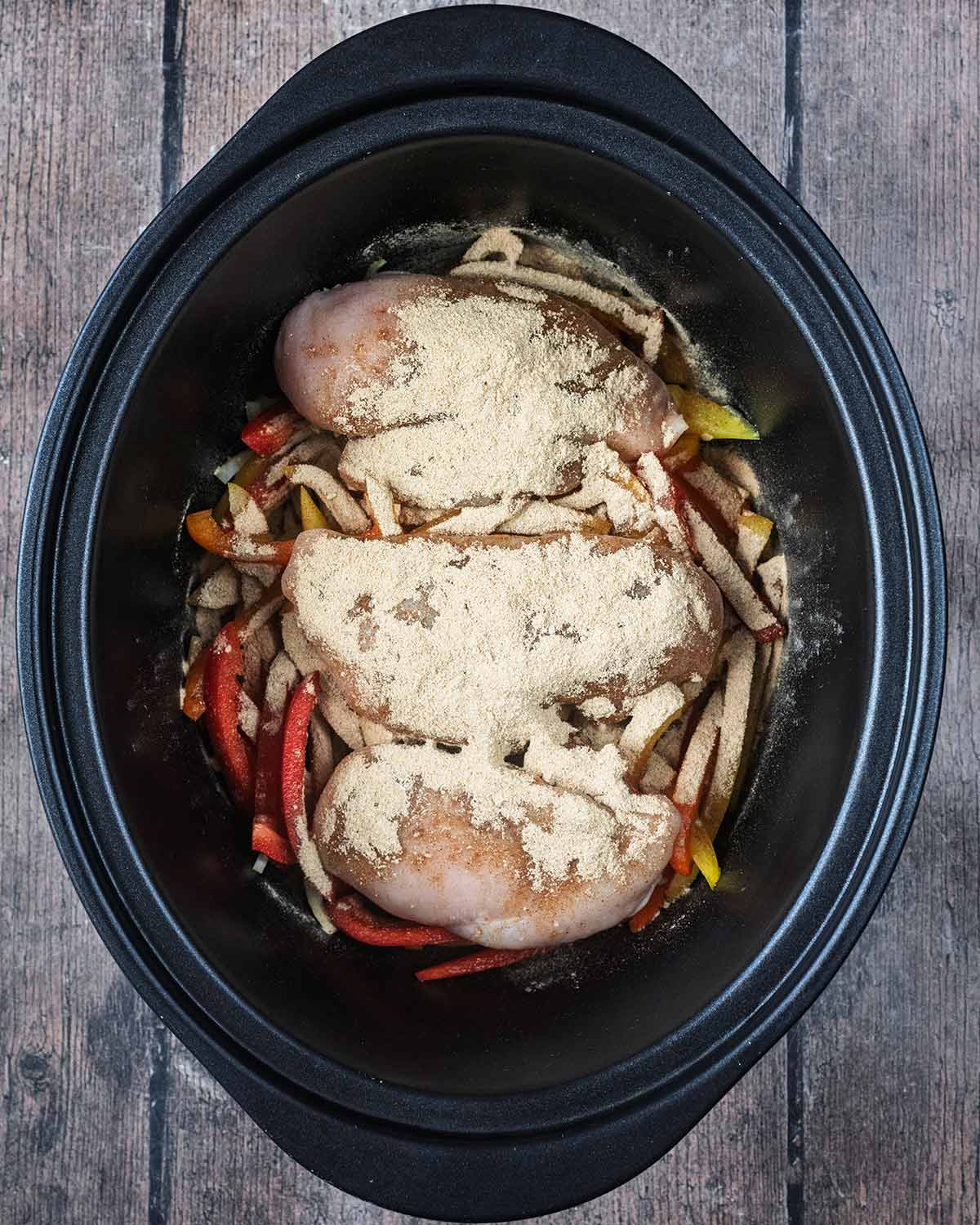 Fajita seasoning sprinkled over everything in the slow cooker.