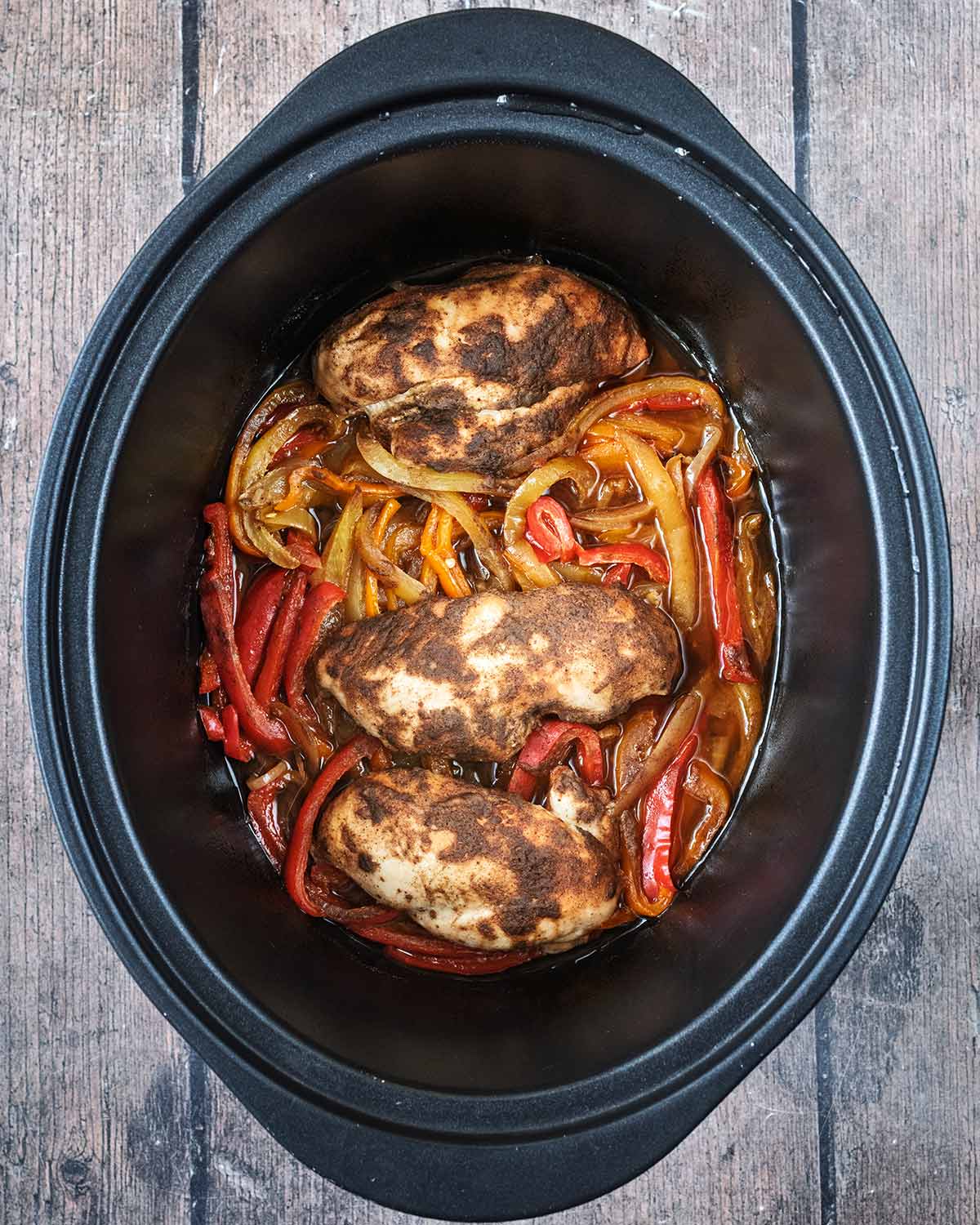 Cooked vegetables and chicken breast in the slow cooker.